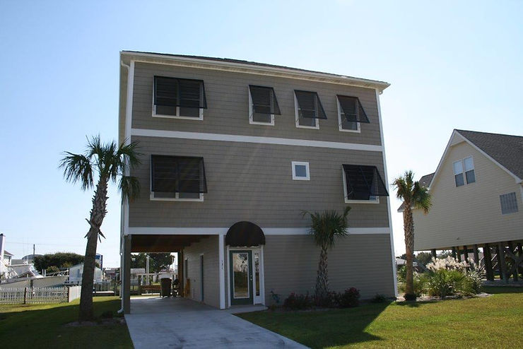 661c5d_22f8ae3f04a7453484dd81a5d Three-story beach house with brown siding, black shutters, and palm trees in the front yard on a sunny North Carolina day, perfect for enjoying the Atlantic breeze.