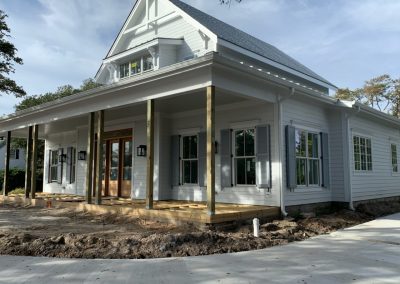 White house with a wide front porch under construction in Morehead City, surrounded by dirt and unfinished landscaping. Roll shutters offer excellent storm protection for coastal homes like this.