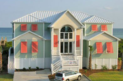 ebbd78_254cb1e205f147dcbb252a1a9 Two-story pastel beach house with red shutters, white stairs, and a car parked in the driveway by the ocean—an inviting Atlantic Breeze escape near Morehead City, North Carolina.