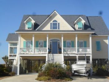 ebbd78_89dc60536b7c403389f5f6755 A two-story, light yellow beach house on stilts with turquoise storm shutters offers storm protection in charming Morehead City, with a boat parked in the driveway.